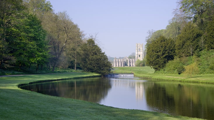 A view over the Half Moon Pond and weir of Studley Royal Water Garden towards Fountains Abbey, North Yorkshire
